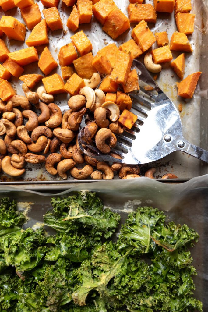 roasted sweet potato, cashews, kale on a baking sheet