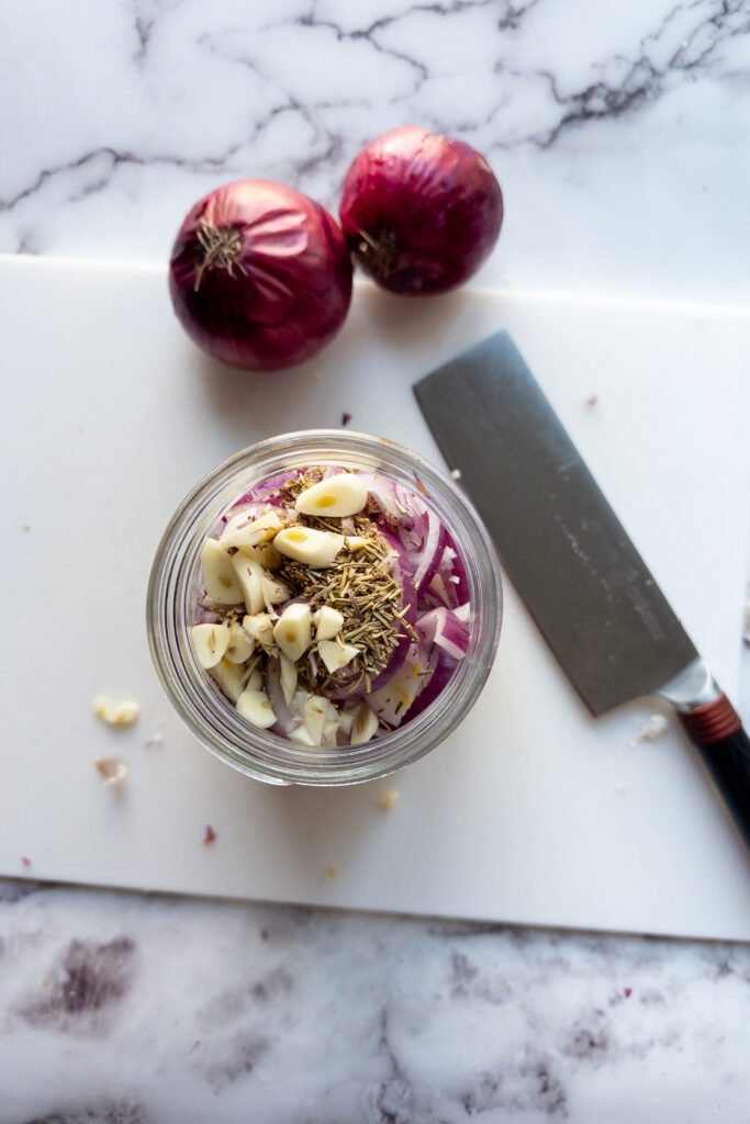 red onions cut in slices and placed in a jar with herbs and garlic on top