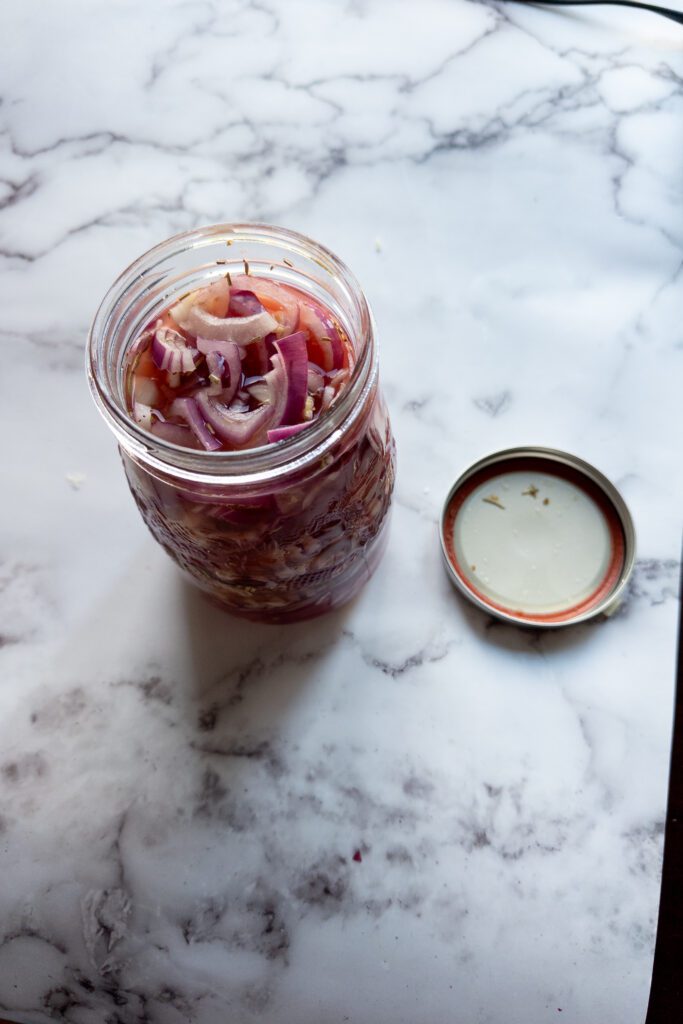 red onions are cut in slices and placed in a jar soaked in vinegar