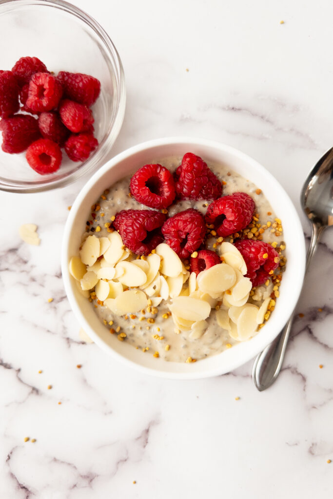 raspberry chia pudding in a bowl with bowl of raspberries beside it