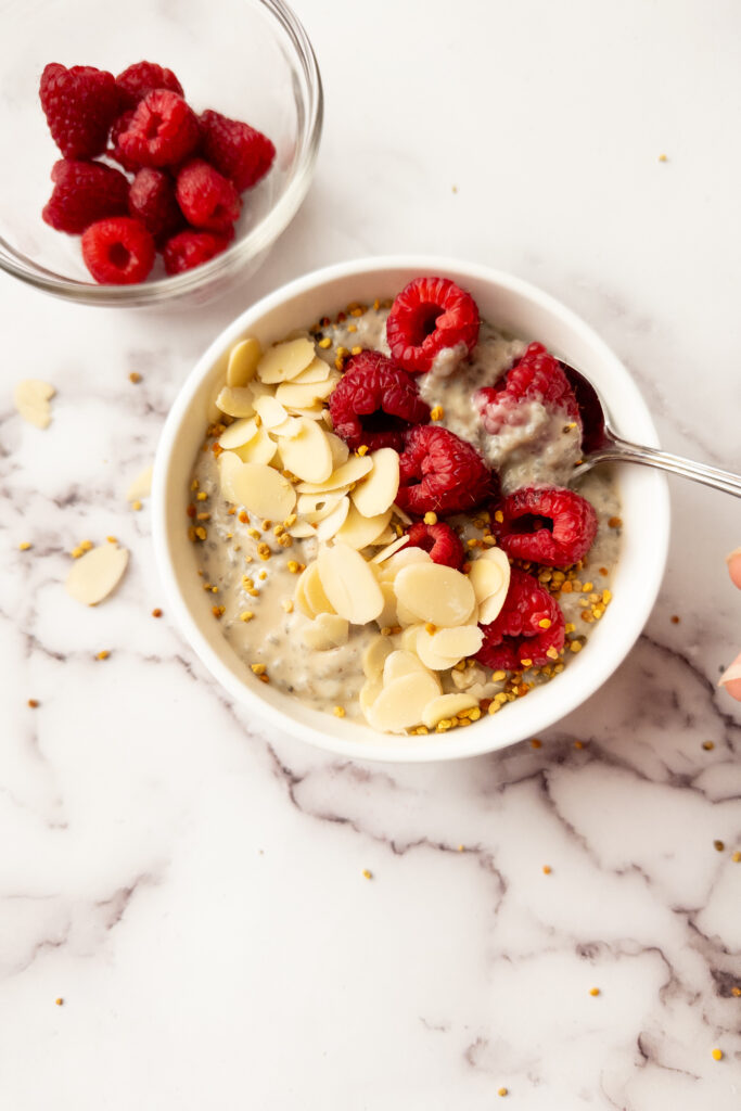 raspberry chia pudding in a bowl with bowl of raspberries beside it