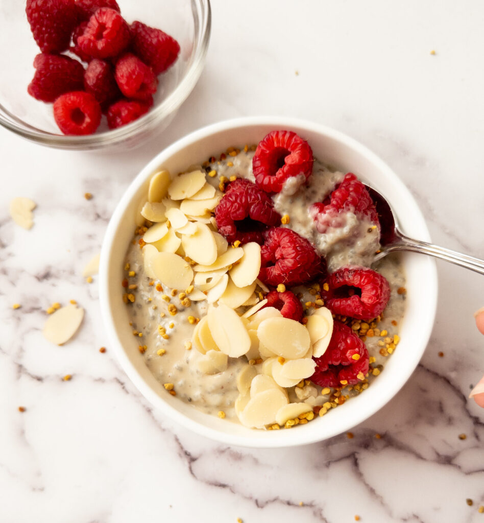 raspberry chia pudding in a bowl with bowl of raspberries beside it